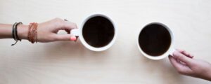 To kaffekopper med hænder fra hver sin side.